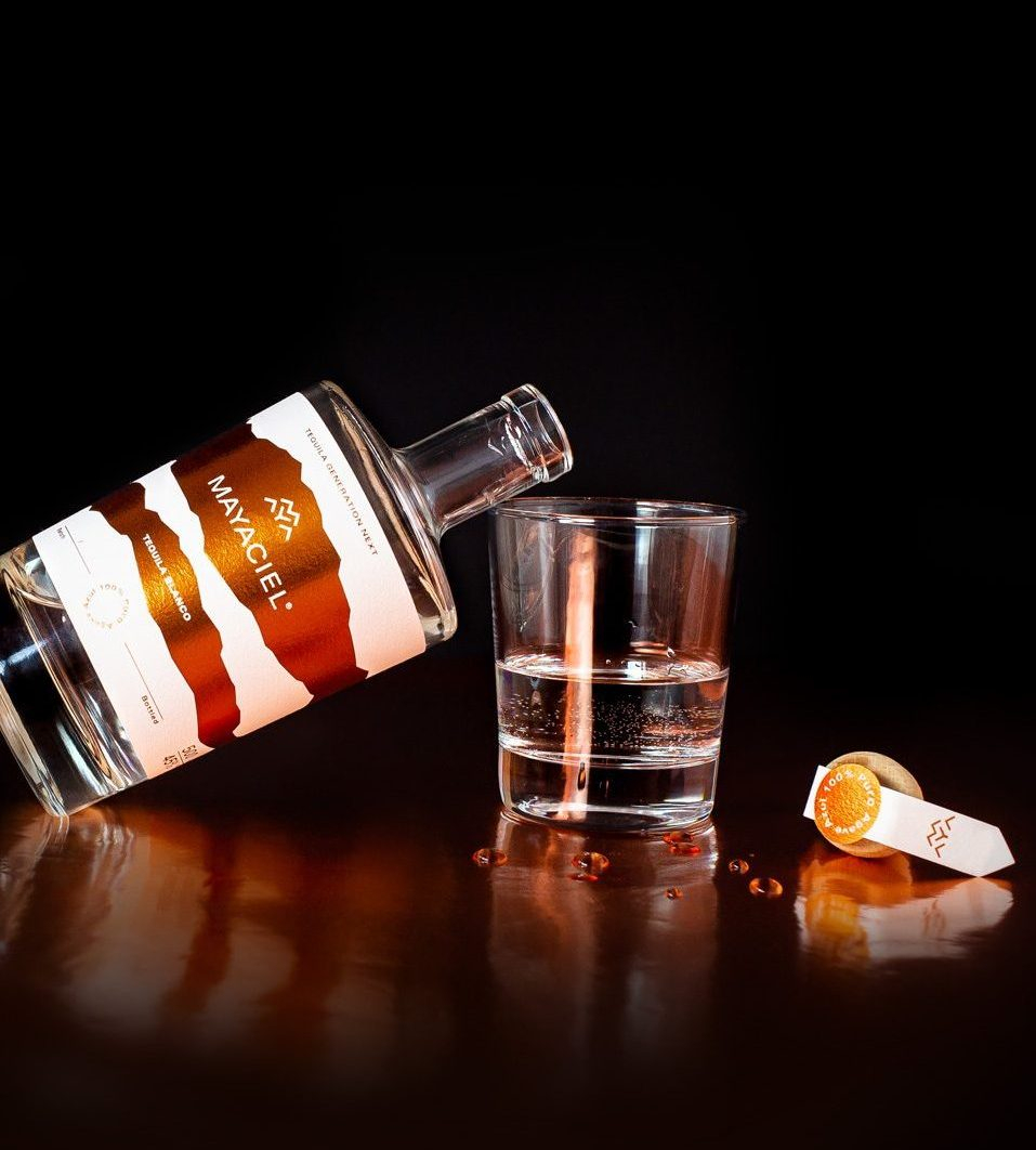 MAYACIEL Tequila Blanco Flasche geöffnet an ein Glas lehnend